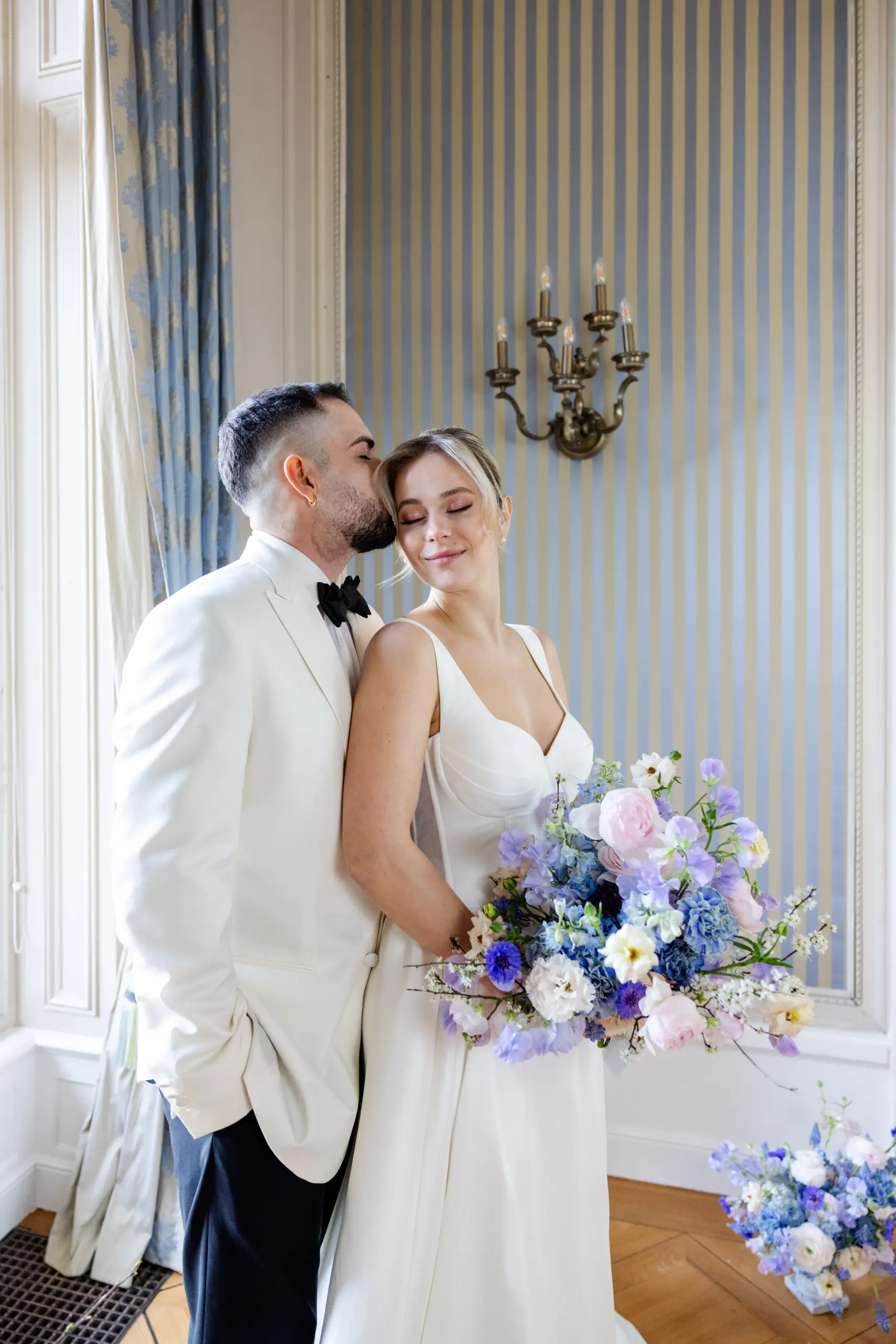 Ein Hochzeitspaar in einer Bridgerton-Kulisse mit sanften Blautönen und weiß.